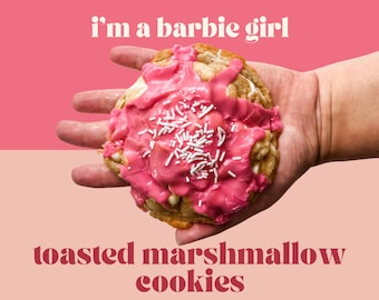 May include: A pink frosted cookie with white sprinkles, held in a hand. The cookie is a toasted marshmallow cookie and the text "i'm a barbie girl" is above the cookie and "toasted marshmallow cookies" is below the cookie.
