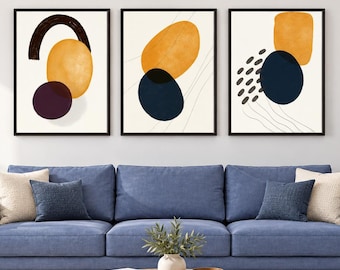 Può includere: Un set di tre stampe d'arte da parete incorniciate con forme astratte in giallo senape, blu scuro e nero su sfondo crema. Le stampe sono esposte in cornici nere sopra un divano blu, mostrando forme geometriche e motivi a linee sottili.