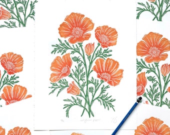 May include: A collection of prints featuring orange California poppies with green stems and leaves. The prints are arranged in a grid pattern on a white surface. The text "California Poppies" is written on one of the prints.