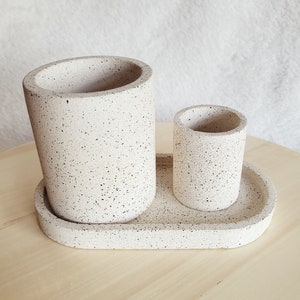 May include: A white speckled ceramic tray with two matching speckled ceramic cups. The larger cup is taller than the smaller cup.