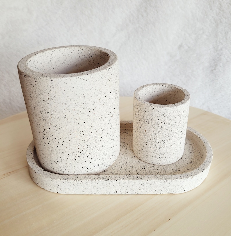 May include: A white speckled ceramic tray with two matching speckled ceramic cups. The larger cup is taller than the smaller cup.