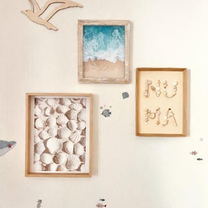 May include: Coastal-themed wall art featuring framed images of a beach scene, seashells, and the word "NU MIA" spelled out with shells. A wooden seagull decorates the wall, with sea life decals.