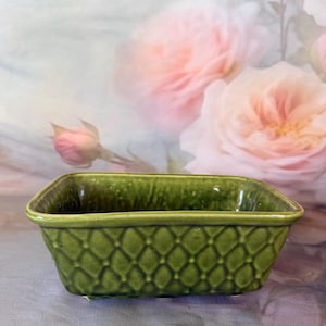 May include: A rectangular ceramic planter with a glossy olive green finish and a raised diamond lattice pattern on the exterior. The vessel features a smooth, slightly flared rim and a deep interior basin, showcasing a consistent glazed texture.