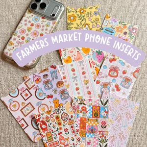 May include: A selection of Farmers Market phone inserts with diverse, colourful patterns. Designs feature floral, fruit, and animal motifs. A phone case with a floral design is also visible.