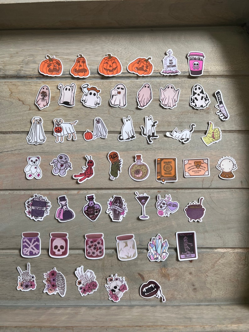 Peut inclure: Un ensemble de 36 autocollants sur le th&egrave;me d'Halloween avec des citrouilles, des fant&ocirc;mes, des chats, un chaudron de sorci&egrave;re, un cr&acirc;ne, une fiole de potion, un cristal, un squelette, un cercueil, et plus encore.