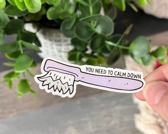 Puede incluir: Una pegatina de cepillo de dientes morado con el texto "You need to calm down".