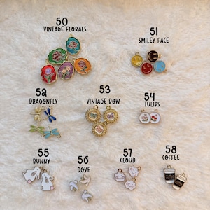 May include: A collection of small, colorful charms with various designs, including flowers, smiley faces, dragonflies, bows, tulips, bunnies, doves, clouds, and coffee cups. The text "MISC. CHARMS" is visible at the bottom.