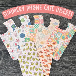 May include: Six different phone case inserts with various summery patterns. The patterns include seashells, fish, pickles, and flowers. The inserts are all white with colorful designs.