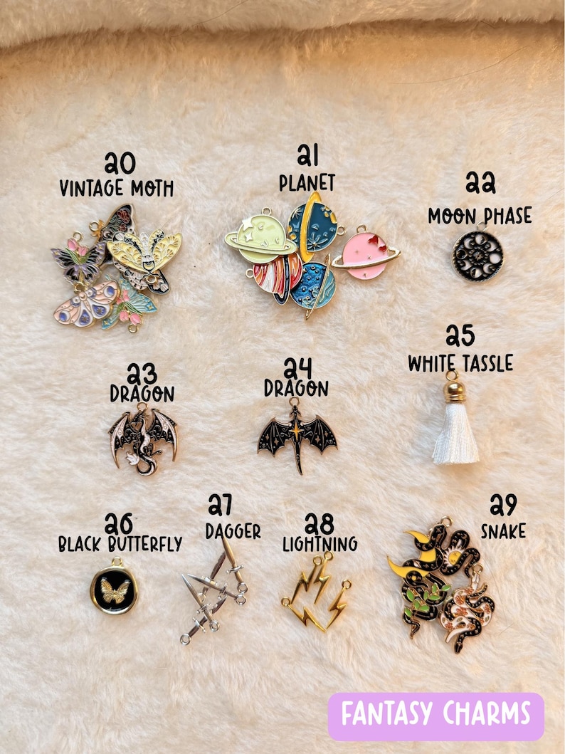 May include: A collection of fantasy-themed charms, including a vintage moth, planets, a moon phase, dragons, a white tassel, a black butterfly, daggers, lightning bolts, and a snake. The charms are in various colors and designs.