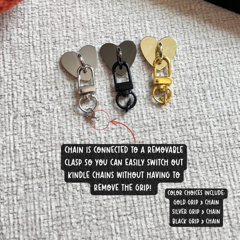 May include: Three heart-shaped clasps in gold, silver, and black, each with a matching chain. The text reads: "CHAIN IS CONNECTED TO A REMOVABLE CLASP SO YOU CAN EASILY SWITCH OUT KINDLE CHAINS WITHOUT HAVING TO REMOVE THE GRIP!"