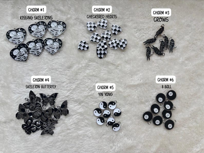 May include: A collection of charms with various designs, including kissing skeletons, checkered hearts, crows, skeleton butterflies, yin yang symbols, and 8-ball designs. Each charm is labeled with a number and a descriptive title.