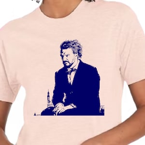 May include: A navy blue t-shirt with a graphic of a man with a beard and mustache wearing a suit and sitting in front of a building.