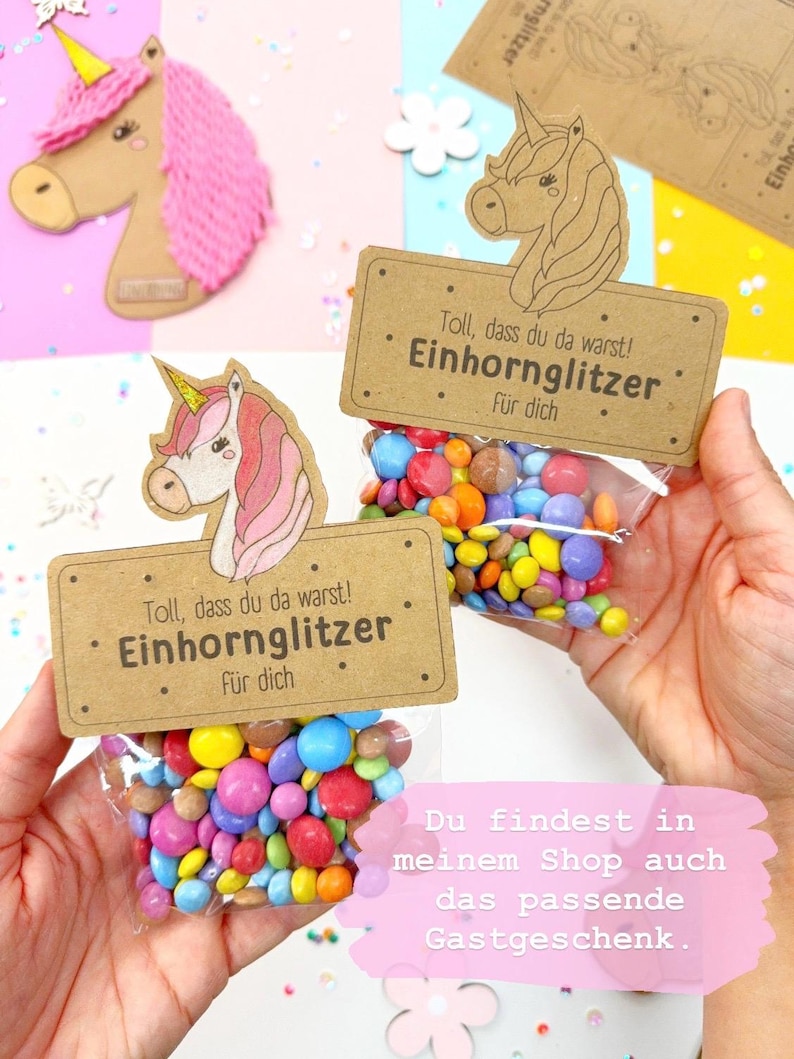 Puede incluir: Dos peque&ntilde;as bolsas de caramelos de colores con una etiqueta con tem&aacute;tica de unicornio que dice "Toll, dass du da warst! Einhornglitzer f&uuml;r dich". La etiqueta es marr&oacute;n con texto blanco y una ilustraci&oacute;n de unicornio.