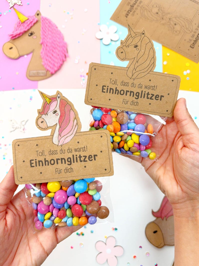 May include: Two small brown paper bags with unicorn illustrations and the text "Toll, dass du da warst! Einhornglitzer F&uuml;r dich" filled with colorful candy.