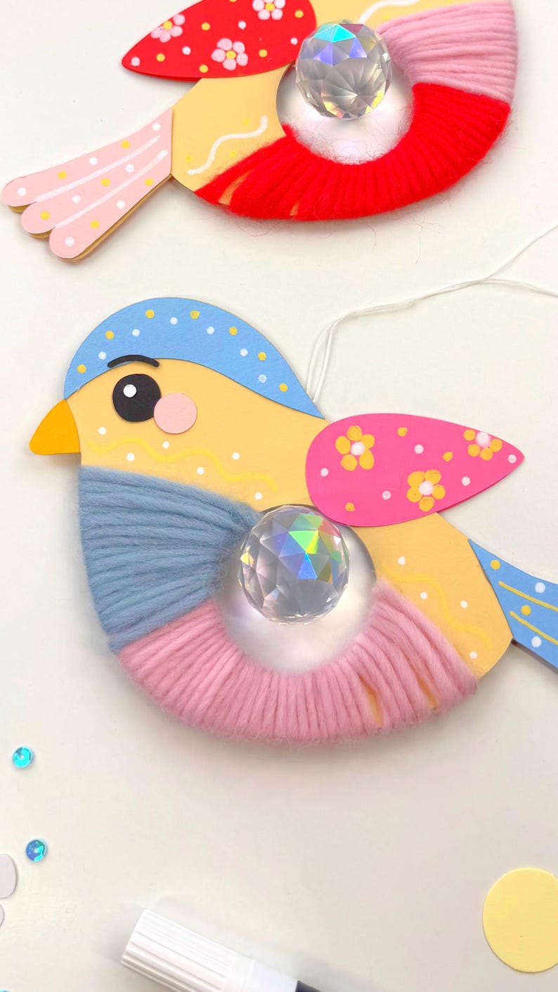 K&ouml;nnte beinhalten: Handgefertigte Vogelornamente mit gelben, blauen, rosa und roten Akzenten. Jeder Vogel hat einen Kristallschmuck und Garndetails. Die Fl&uuml;gel sind mit floralen Mustern verziert. Diese skurrilen Dekorationen sind perfekt, um jedem Raum einen Farbtupfer zu verleihen.