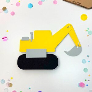 Puede incluir: Un veh&iacute;culo de construcci&oacute;n amarillo con una pala gris, ruedas negras y una tarjeta marr&oacute;n con el texto "Einladung zu meinem Geburtstag". El veh&iacute;culo est&aacute; rodeado de confeti de colores.
