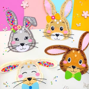 Puede incluir: Cuatro caras de conejo de papel de colores con detalles de purpurina y lazos. Los conejos tienen mejillas rosadas y bigotes negros. El fondo es un collage de papel de colores.