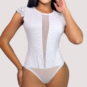 White bridal lace bodysuit for women with deep plunge sheer mesh front, round neckline, cap sleeves, thong back, and snap closure. Elegant floral lace details create a sensual and sophisticated silhouette for honeymoon or wedding night wear.