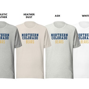 Puede incluir: Cuatro camisetas de diferentes colores: gris deportivo, polvo de brezo, ceniza y blanco. Cada camiseta tiene el texto "NORTHERN COLORADO BEARS" en letras azul marino y doradas.