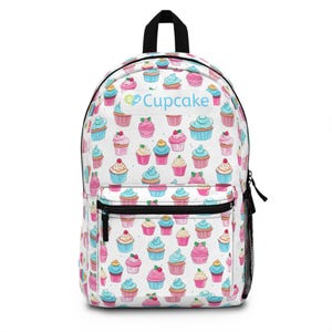 May include: White backpack covered in a pattern of colorful cupcakes with blue, pink, and yellow frosting. The word "Cupcake" is printed on the front. The backpack has a black zipper, a side pocket, and a top handle.