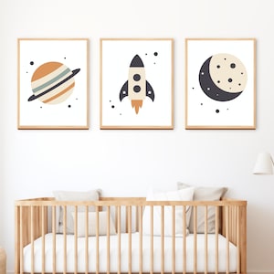 May include: Three framed prints with a space theme. The prints feature a planet with rings, a rocket ship, and a crescent moon.