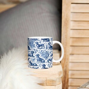 May include: A white ceramic mug with a blue and white pattern of dachshunds. The mug has a handle and is sitting on a wooden surface.