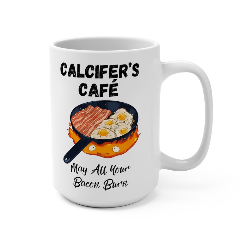 May include: White ceramic mug with a black and white illustration of a frying pan with bacon and eggs on fire. The text "Calcifer's Cafe" and "May All Your Bacon Burn" is printed on the mug.
