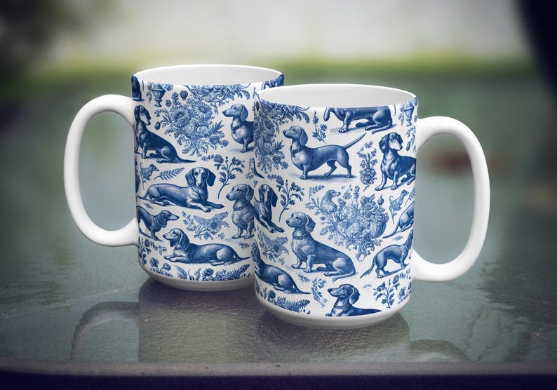 May include: Two white ceramic mugs with blue and white dachshund patterns. The mugs are 11 ounces and are dishwasher and microwave safe.