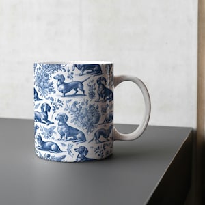 May include: A white ceramic mug with a blue and white pattern of dachshunds. The mug has a handle and is filled with a white liquid.