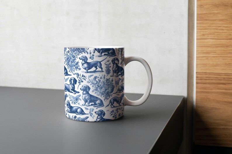 May include: A white ceramic mug with a blue and white pattern of dachshunds. The mug has a handle and is filled with a white liquid.