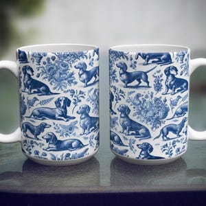 May include: Two white ceramic mugs with a blue and white pattern of dachshunds. The mugs have a handle on the right side.