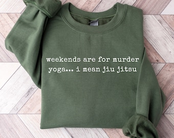 Può includere: Felpa verde con la scritta "weekends are for murder yoga... i mean jiu jitsu" stampata in bianco.