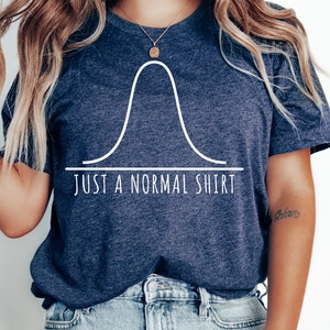 May include: A dark blue t-shirt with a white graphic of a bell curve and the text "JUST A NORMAL SHIRT".
