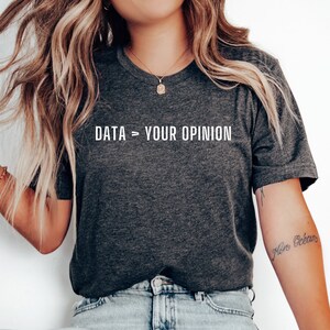 May include: A dark gray t-shirt with the text "DATA > YOUR OPINION" printed in white on the front.