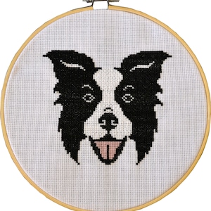 Könnte beinhalten: Eine schwarze und weiße Kreuzstich-Stickerei eines Border Collie-Hundegesichts mit herausgestreckter rosa Zunge. Die Stickerei ist in einem Holzrahmen eingefasst.