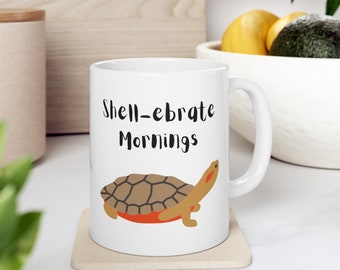May include: White ceramic coffee mug with a brown turtle illustration and the text "Shell-ebrate Mornings".