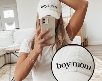 Peut inclure: Casquette de baseball blanche avec l'inscription brodée "boy mom" en noir. La casquette est en tissu doux et possède une visière incurvée. Un accessoire décontracté.