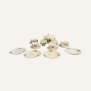 May include: A vintage tea set with a white background and a green and brown floral design. The set includes a teapot, sugar bowl, creamer, and four cups and saucers.
