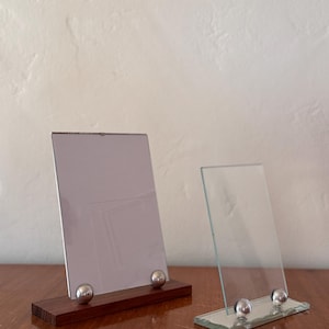 May include: A white ceramic mug with a black handle and the text "But First, Coffee" in a black, bold font. The mug is sitting on a wooden surface.