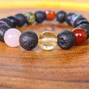 May include: A bracelet made of black lava rock beads with various coloured gemstone beads, including pink, red, yellow, and green.
