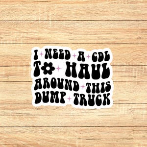 May include: A black and white sticker with the text "I need a CDL to haul around this dump truck" in a retro font. The text is surrounded by small stars and a pink flower.