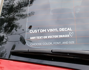 May include: White vinyl decal on a car window that says "CUSTOM VINYL DECAL" and "ANY TEXT OR VECTOR IMAGES" with a heart symbol. The decal also says "CHOOSE COLOR, FONT, AND SIZE".