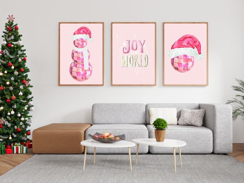 May include: Three pink framed prints with a pink and white snowman, a pink disco ball with a Santa hat, and the text "JOY TO THE WORLD" in pink and yellow.
