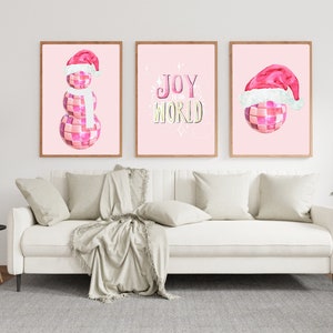 May include: Three pink and white Christmas-themed prints with a pink disco ball snowman, a pink disco ball with a Santa hat, and the text "JOY WORLD" in gold and yellow letters.