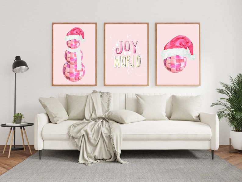 May include: Three pink and white Christmas-themed prints with a pink disco ball snowman, a pink disco ball with a Santa hat, and the text "JOY WORLD" in gold and yellow letters.