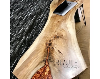 Può includere: Una scrivania in legno a bordo vivo con un fiume di resina epossidica color rame che attraversa il centro. La scrivania ha gambe a forcina nere e un laptop e un mouse sono sulla superficie. Il testo "RIVULET tables design" è sulla scrivania.