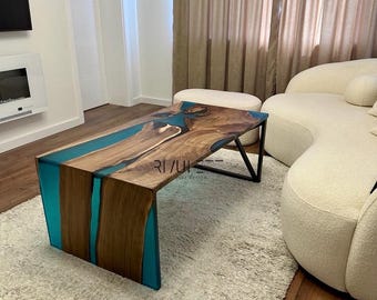 May include: A teal and brown coffee table with a unique epoxy resin design. The table has a black metal frame and is sitting on a white shag rug.