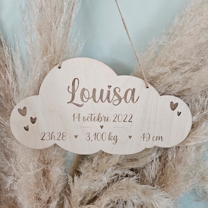 Puede incluir: Un letrero de madera en forma de nube con el nombre "Louisa" grabado en él. El letrero también incluye la fecha "14 octobre 2022", la hora "23h28", el peso "3,100 kg" y la longitud "49 cm".