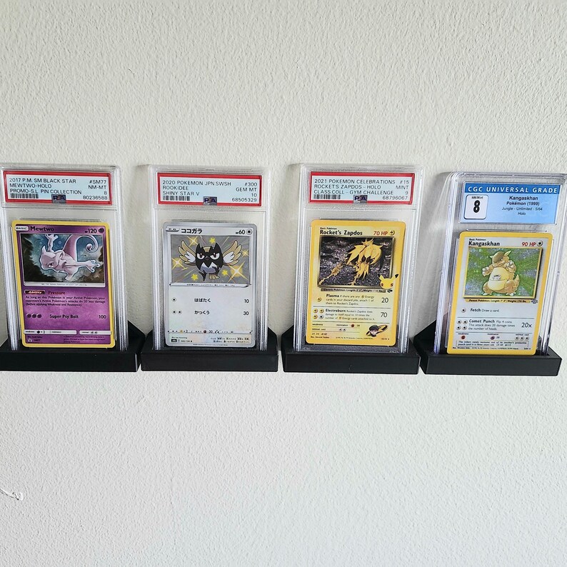 Puede incluir: Cuatro cartas de intercambio de Pok&eacute;mon se muestran en estuches protectores. Las cartas est&aacute;n calificadas por CGC Universal Grade y presentan a Mewtwo, Kokoara, Rocket's Zapdos y Kangaskhan. Las cartas est&aacute;n en excelente estado y tienen una calificaci&oacute;n alta.