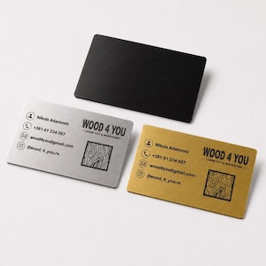 Op de afbeelding: Drie rechthoekige visitekaartjes in zwart, zilver en goud. De zilveren en gouden kaarten bevatten de tekst WOOD 4 YOU, contactgegevens voor Nikola Adamović, telefoonnummer +381 61 234 567, e-mail wood4you@gmail.com en een houtnerfpictogram.